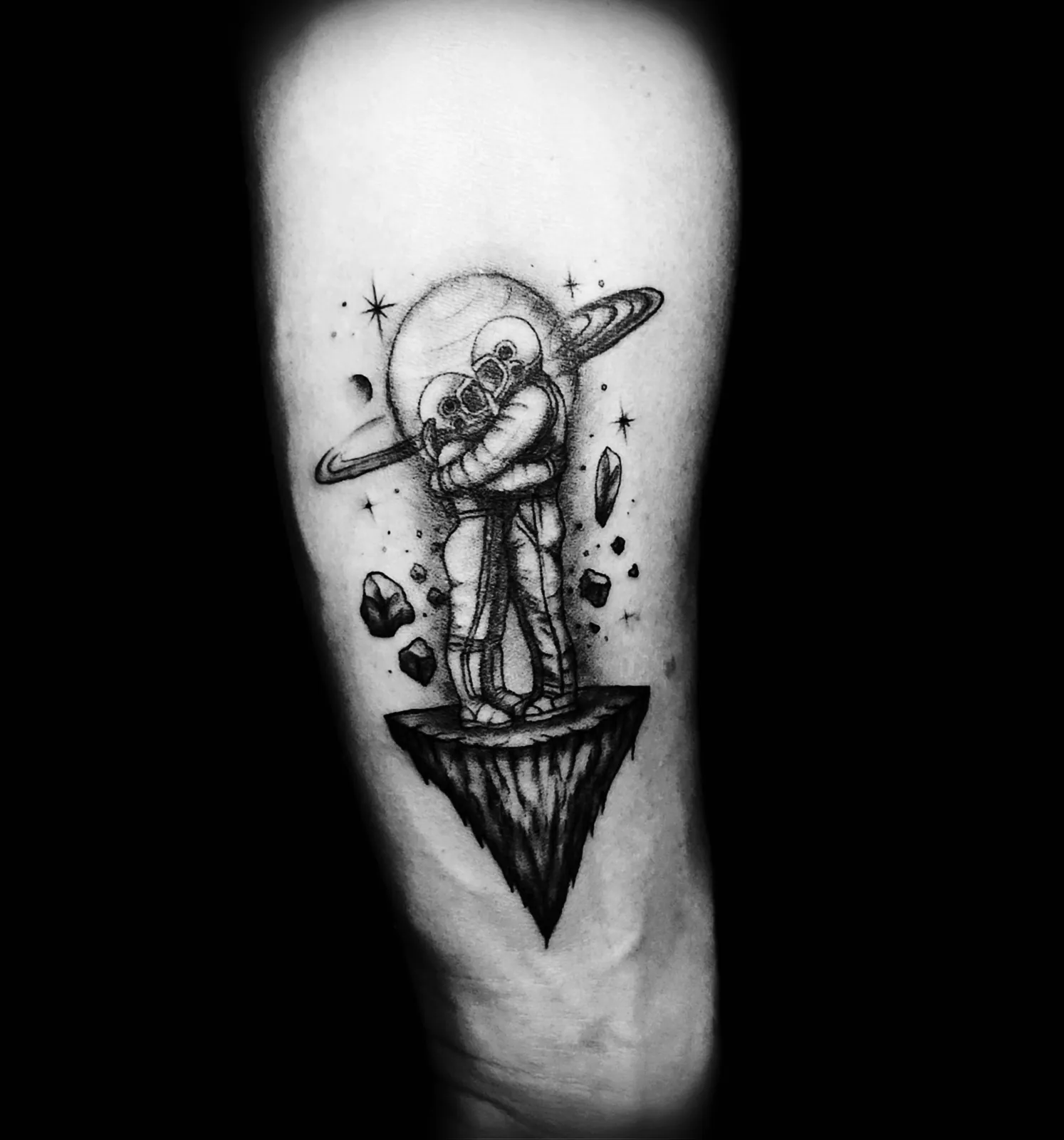 Delikatny tatuaż fine line dwóch astronautów w objęciach na tle planety, wykonany w PM Tattoo w Legnicy