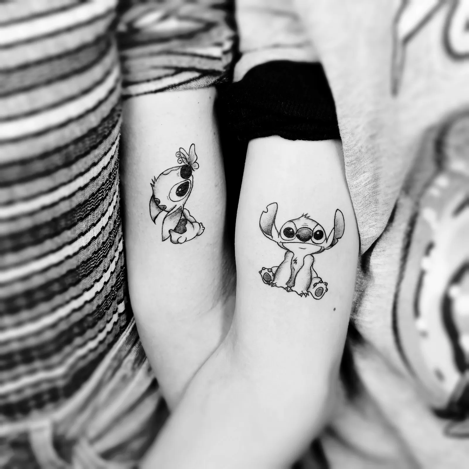 Dwa małe tatuaże bajkowych postaci na przedramionach dwóch osób, wykonane w PM Tattoo w Legnicy