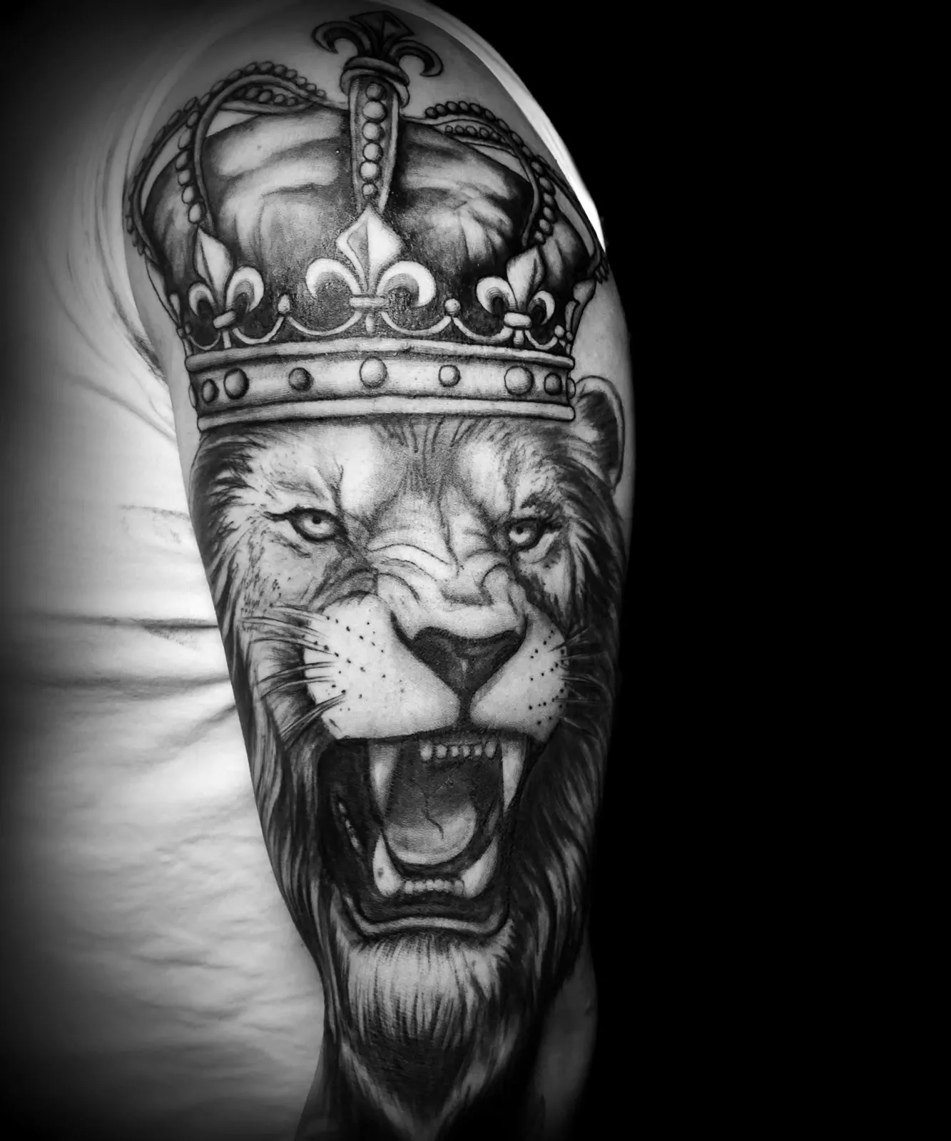 Realistyczny tatuaż ryczącego lwa w koronie na ramieniu, wykonany w PM Tattoo w Legnicy