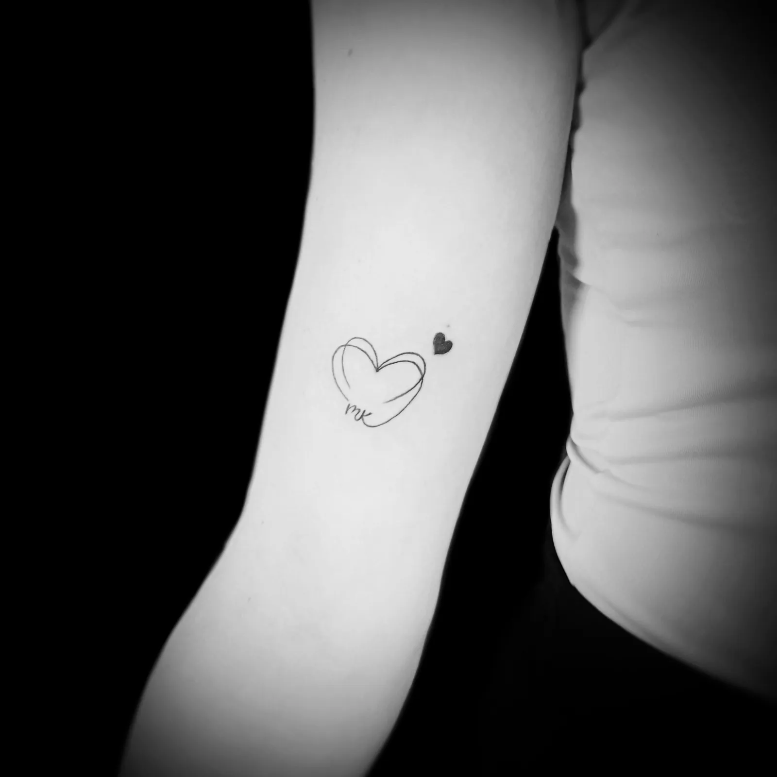 Minimalistyczny tatuaż serca z napisem na ramieniu, wykonany w PM Tattoo w Legnicy