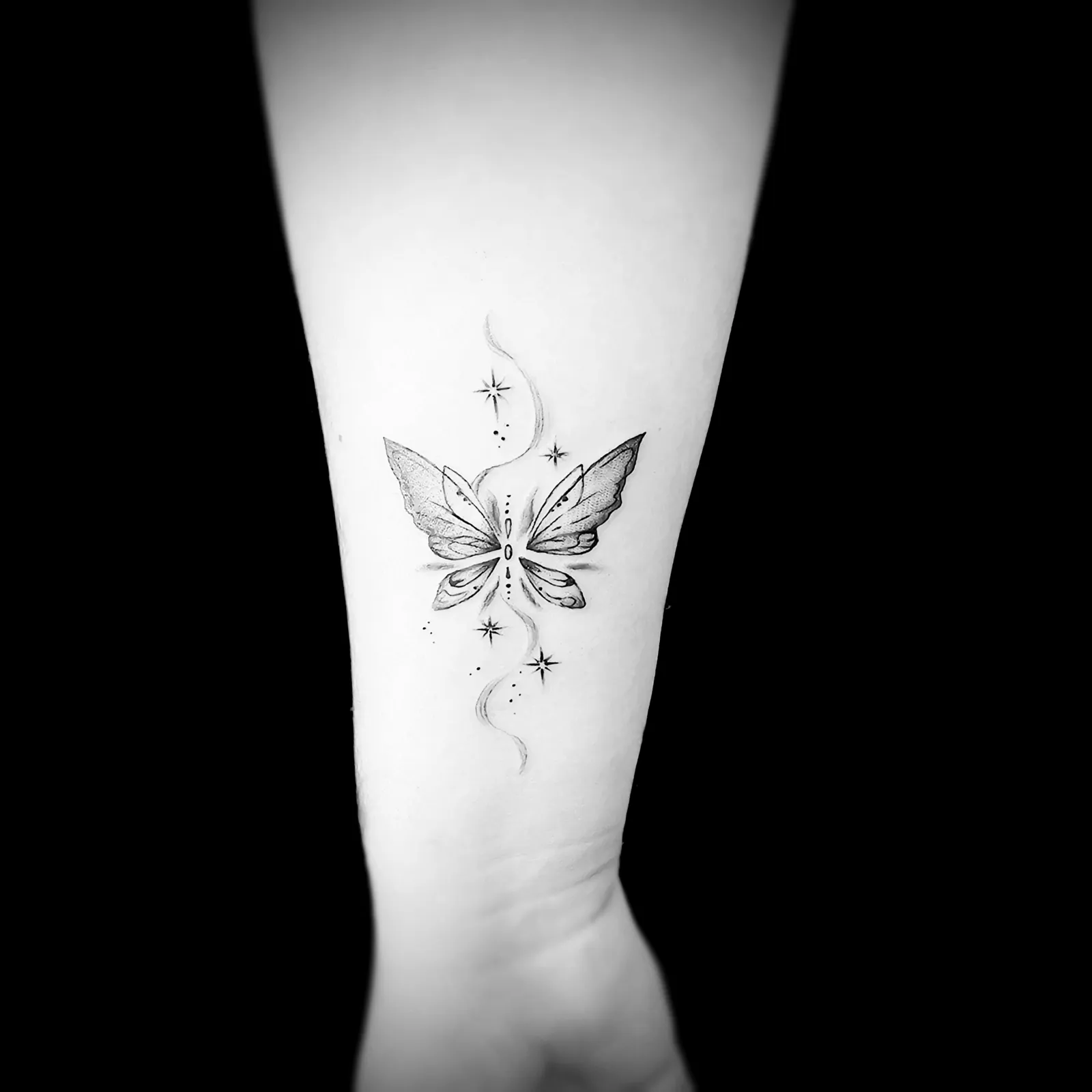 Tatuaż fine line motyla z gwiazdkami na przedramieniu, wykonany w PM Tattoo w Legnicy